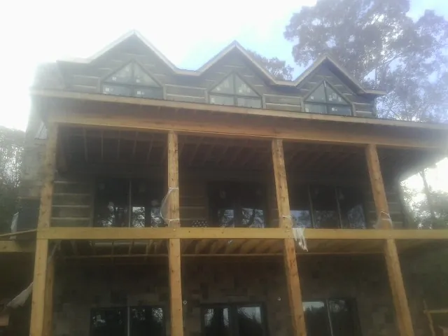 Dormers and porch framing on a large log home under construction — Roof Coating work by our crew in Bolton